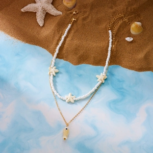 Detail of layered ocean necklace with white beads, starfish charms, and yellow fish pendant