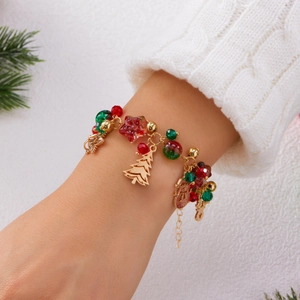 Close-up of Christmas charm bracelet with festive red and green beads and golden bells