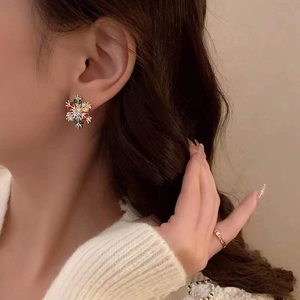 Elegant gold snowflake earrings with multicolor zircon stones worn by a female model