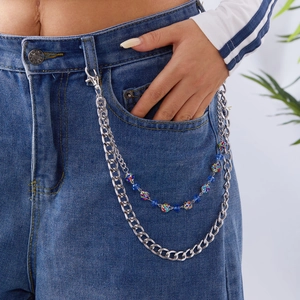 Détail d'une chaîne de pantalon en alliage argenté avec perles bleues sur denim