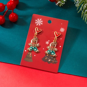 Détails des boucles d'oreilles bonhomme de pain d'épices sur carte de Noël rouge