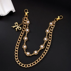 Détail d'une double chaîne cubaine dorée avec perles blanches et pendentif nœud élégant