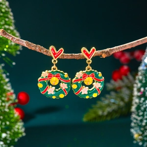 Gros plan de boucles d'oreilles couronne de Noël avec nœud rouge et cloche dorée