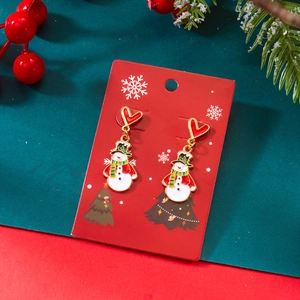 Gros plan de boucles d'oreilles bonhomme de neige avec crochets cœur sur fond de sapin festif