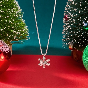 Macro detail of silver snowflake necklace pendant with sparkling crystals on red surface