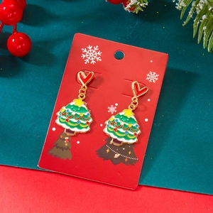 Détail de boucles d'oreilles sapin de Noël avec puces cœur rouge et décor de fête