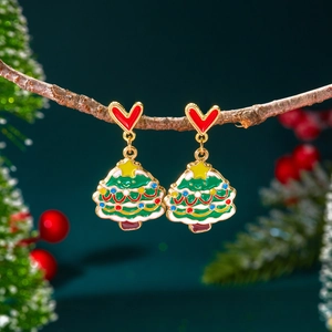Détail des boucles d'oreilles sapin de Noël avec puces cœurs rouges sur branche