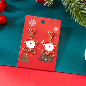 Détail de boucles d'oreilles Père Noël en émail sur carte de présentation festive