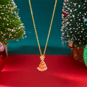 Macro view of gold Christmas tree pendant with red enamel and sparkling zircon accents