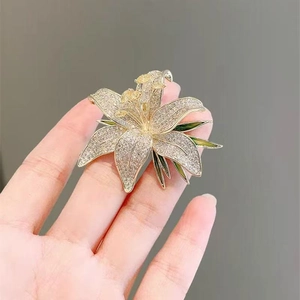 Détail de la broche fleur de lys avec cristaux blancs et émail vert sur base dorée