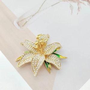 Vue détaillée d'une broche lys avec cristaux blancs et émail vert sur fond élégant