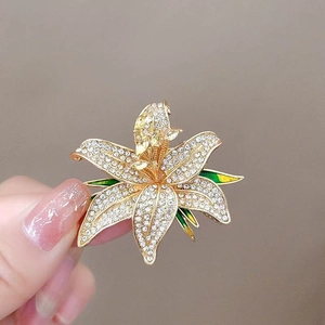 Détail macro de broche lys avec cristaux blancs et feuille en émail vert