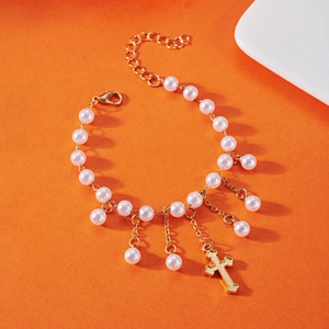 Collier à pendentif croix avec perles et pompon doré sur fond orange vif élégant