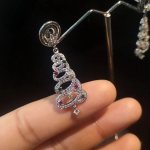 Close-up of sparkling Christmas tree drop earrings with colorful gemstones and tassel