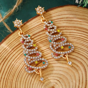 Macro detail of gold-plated Christmas tree earrings with colorful crystals on wood