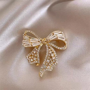 Gros plan d'une broche nœud dorée ornée de zircons sur un fond en soie de couleur champagne