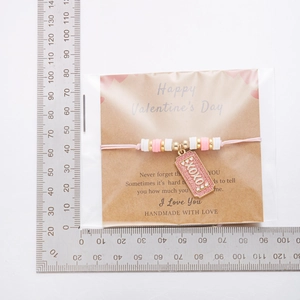 Pulsera trenzada rosa con corazón en tarjeta de San Valentín y detalle de XOXO