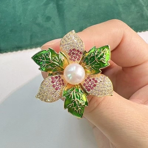 Détail d'une broche florale avec une perle centrale et des pétales en zircone