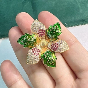 Vue détaillée d'une broche florale avec feuilles d'émail vert et zircons rubis incrustés