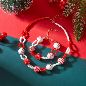 Detailopname van de rood-witte kerstkraal ketting en armband set met sneeuwpop motief