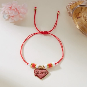 Detalle macro de pulsera de cuerda roja con colgante de corazón y grabado de Love