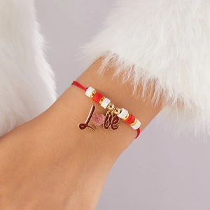 Detalle de pulsera de cuentas rojas y blancas con colgante de corazón Love en la muñeca