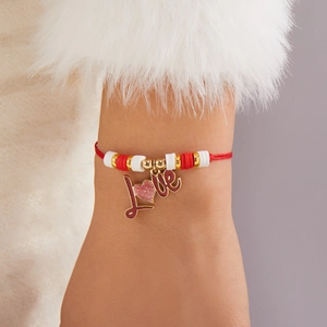 Detalle de pulsera tejida roja con colgante de corazón Love y cuentas de arcilla suave