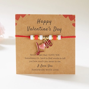 Pulsera trenzada roja con dije de corazón LOVE en una tarjeta de regalo de San Valentín