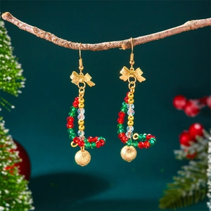 Detail of Christmas beaded drop earrings with golden bow and sphere on a wood branch