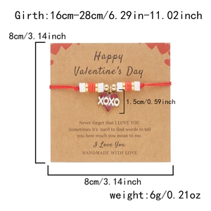Detalle de pulsera trenzada roja con dije XOXO en una tarjeta de San Valentín
