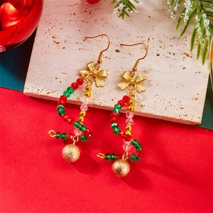 Detailed view of Christmas beaded earrings with golden bows on a textured stone surface