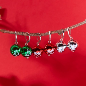Détail des boucles d'oreilles de Noël festives en rouge, vert et argent sur une branche
