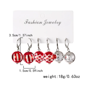 Vue détaillée de trois paires de boucles d'oreilles boules de Noël avec flocons de neige
