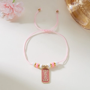 Detalle de pulsera trenzada rosa con amuleto XOXO y cuentas de arcilla polimérica