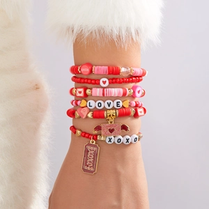 Détail de bracelets LOVE multicouches perlés avec breloques cœur au poignet féminin