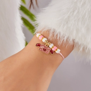 Detalle de pulsera de cuentas con sobre de corazón y alas brillantes en la muñeca del modelo