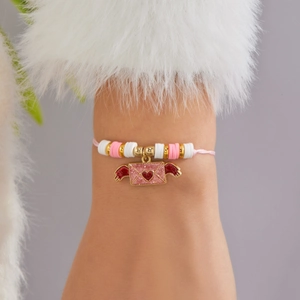 Detalle de una pulsera de cuentas rosas hecha a mano con dije de sobre de corazón