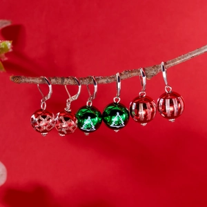 Trois paires de boucles d'oreilles de Noël avec boules rouges et vertes sur bois