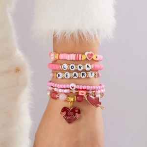 Détail d'un ensemble de bracelets extensibles bohèmes roses avec breloques cœur et perles