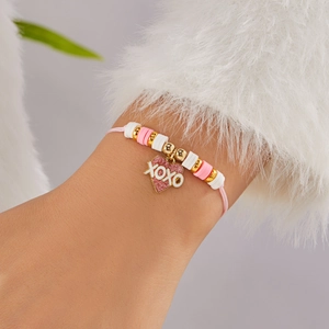 Detalle de colgante de corazón rosa XOXO y pulsera de cuentas en la muñeca