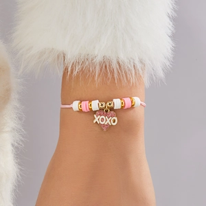 Detalle de pulsera tejida con colgante de corazón XOXO rosa y cuentas suaves