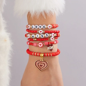 Détail de bracelets multicouches en perles rouges et dorées avec perles LOVE et KISS