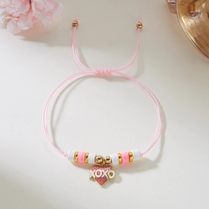 Detalle del colgante de corazón con texto XOXO en pulsera de cuerda trenzada rosa