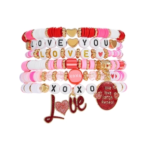 Détail de bracelets multicouches bohèmes roses et rouges avec breloques en forme de cœur