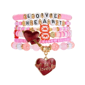 Détail macro du bracelet multicouche en perles roses avec grand pendentif cœur à paillettes