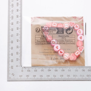 Dettaglio del bracciale fatto a mano con perle a cuore e messaggi d'amore su carta