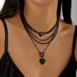 Detail of layered black choker necklace with OT buckle and engraved heart pendant