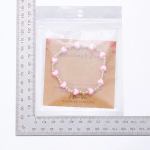 Bracciale di perle a cuore rosa con cartoncino kraft e scala di misurazione reale