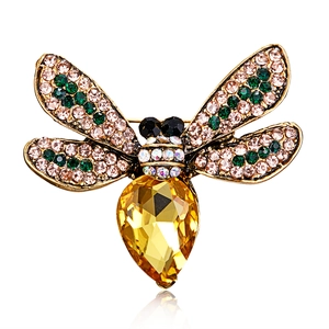 Macro detail of a golden insect brooch featuring a yellow teardrop crystal and colorful wings