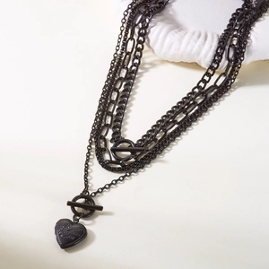 Detail of multi-layer black necklace featuring OT buckle and I Love You heart pendant